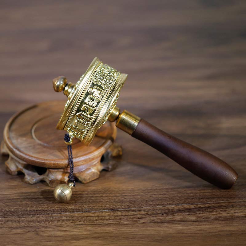 Sandalwood Tibetan Prayer Wheel – Brass cylinder with Tibetan mantra embossed on dark wood handle, cord counterweight, three-quarter view, spiritual craft