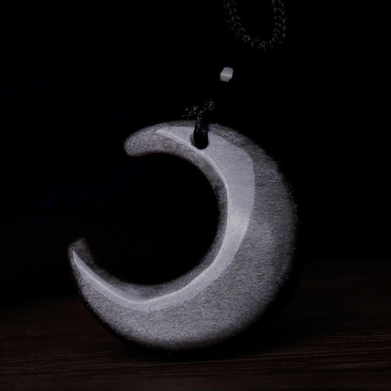 Silver Sheen Obsidian Yin Yang Pendant - White selenite crescent moon on dark wood surface, crystal pendant