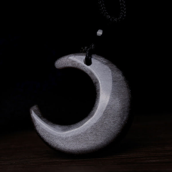 Silver Sheen Obsidian Yin Yang Pendant - White selenite crescent moon on dark wood surface, crystal pendant