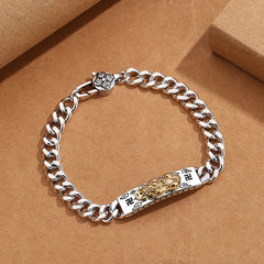 Om Mani Padme Hum PiXiu Swastika Wisdom Bracelet – silver Cuban chain with gold PiXiu centerpiece on brown surface