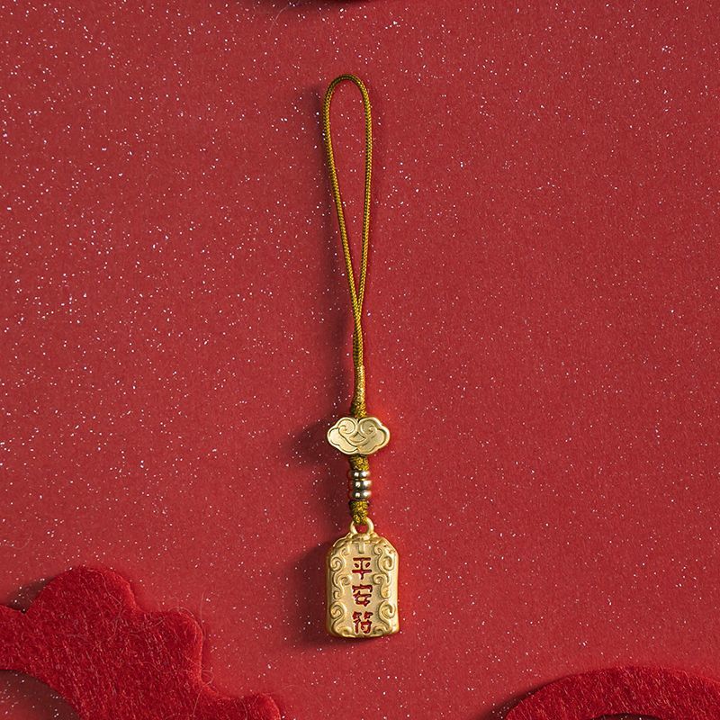 Single brass peace charm with gold cord on red festive background