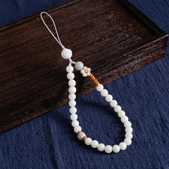 White Jade Bodhi & Jadeite Crystal Phone Charm – White bodhi seed beads with green jadeite accent and carved lotus flower on dark wood tray