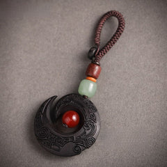 Feng Shui ebony wood protection keychain spiral crescent design with red agate bead on white background