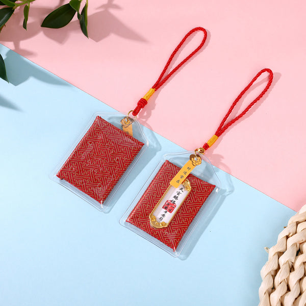 Two red safety blessing amulets on pink and blue background