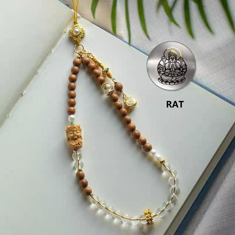Sandalwood & Crystal Zodiac Buddha Phone Charm – Rat zodiac guardian Buddha design with sandalwood beads, clear quartz crystals, pearls, and gold accents on open book with green leaves Main image