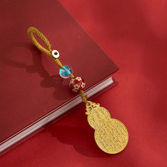 Antique gold gourd keychain with gold cord and blue glass bead on red book