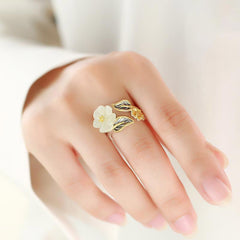 White Jade Plum Blossom Silver Ring - Ring worn on finger with carved white jade flower, gold-edged leaves with dark veining, and small gold flower bud accent