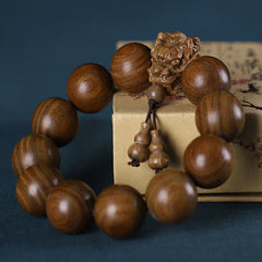 Multi-Wood Dragon Bracelet - Guardian lion carved bead with gourd pendants on teal backdrop, Protection