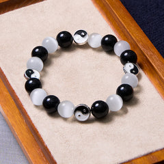 Black Obsidian Cat Eye Yin Yang Bracelet - overhead view in wooden tray with velvet liner, black and white stone bead bracelet