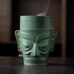 Sanxingdui Bronze Mask Incense Burner – Frontal view with steam rising from lid opening, bronze patina ceramic
