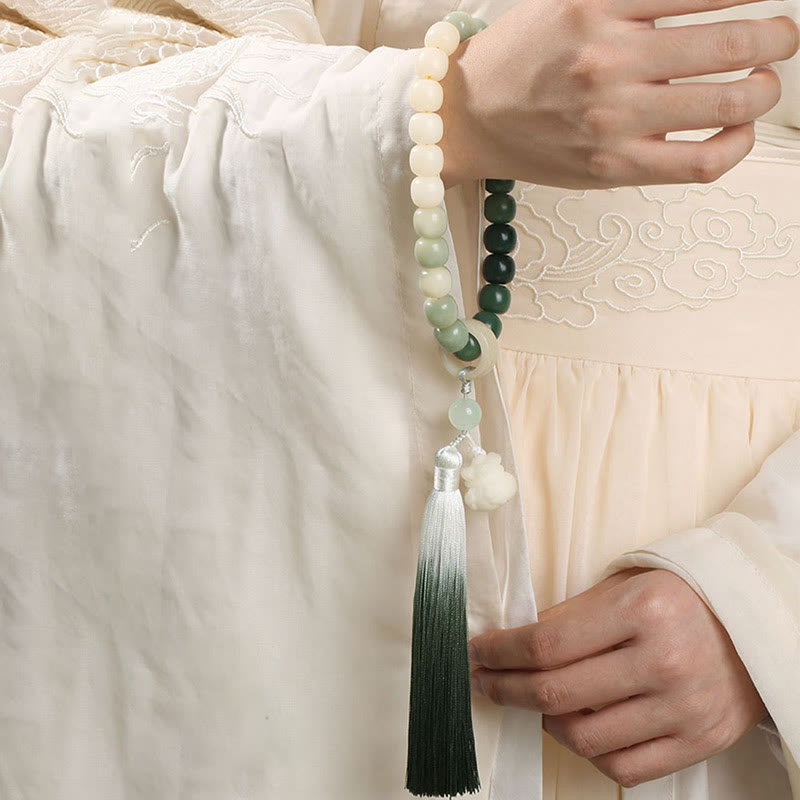 Bodhi Seed Lotus Wisdom Wrist Mala – Handheld mala with lotus finial and ombre tassel, held in hands over dark mat, meditation beads