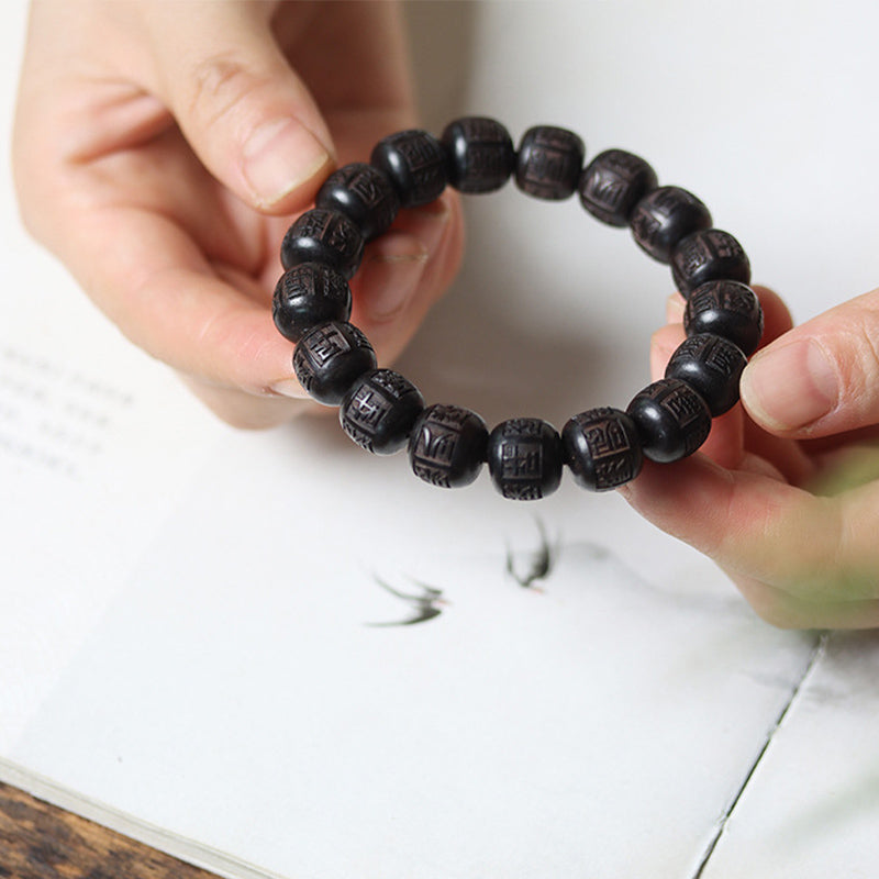 Ebony Wood Mantra Bracelet – Two hands presenting bracelet on white with artful backdrop, spiritual gift