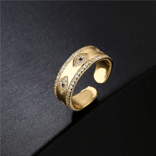 Gold Evil Eye Adjustable Ring with Pavé Crystal Band on Dark Textured Background