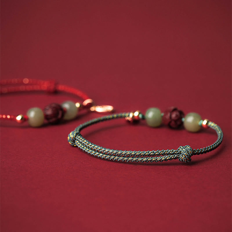 Hetian Jade Cinnabar Lotus Bracelet – Teal cord in focus with soft red cord behind, bokeh bracelet shot