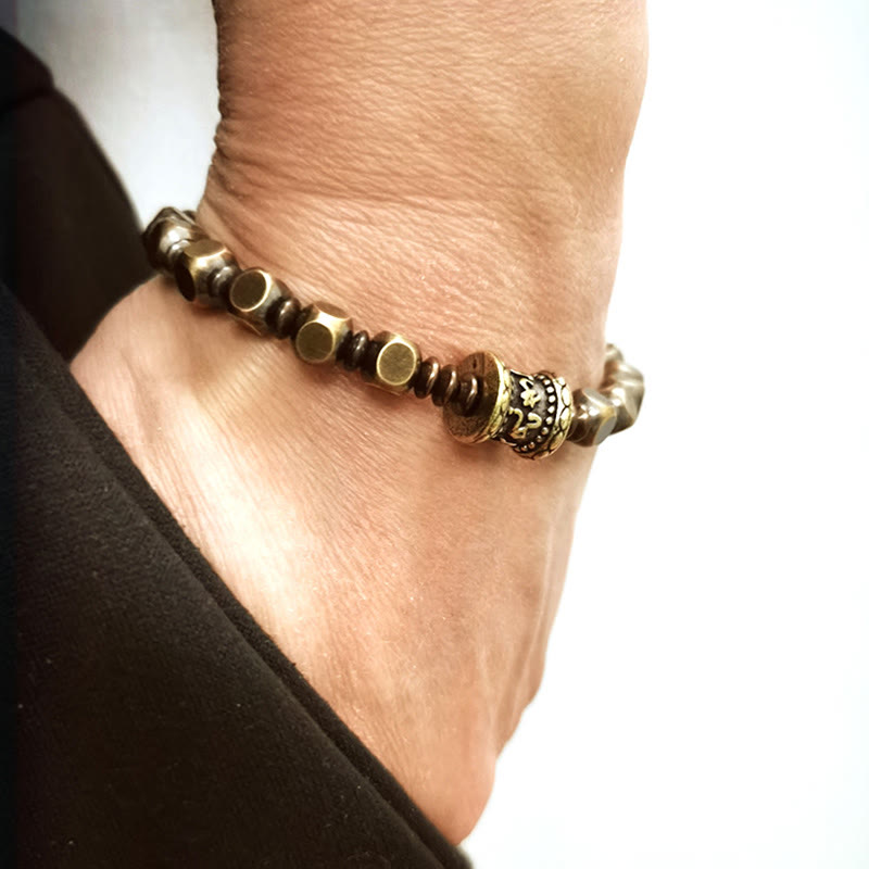 Om Mani Padme Hum Brass Bracelet - Brass beads on wrist near white background with dark sleeve, copper amulet