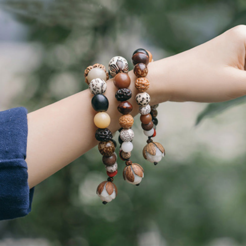 Bodhi Seed Lotus Bracelet – Stacked on wrist against greenery showing lotus pod pendants, peace jewelry