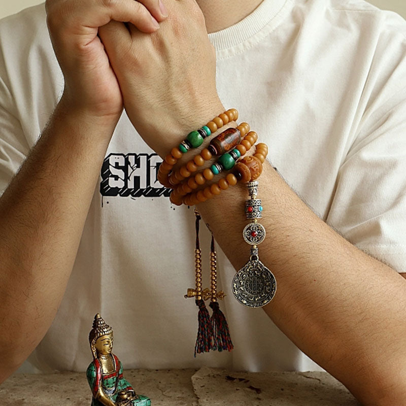 108 Bodhi Seed Mala Bracelet – Multi-wrap bracelet on wrist with tassels beside Buddha statue