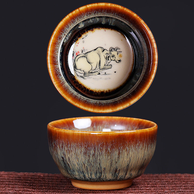 12 Zodiac Jian Zhan Teacup - Ox zodiac overhead view showing hare fur glaze with zodiac motif visible through amber tea