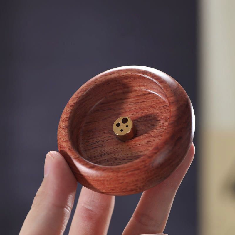 Warm brown wood incense holder with brass insert held in hand, healing