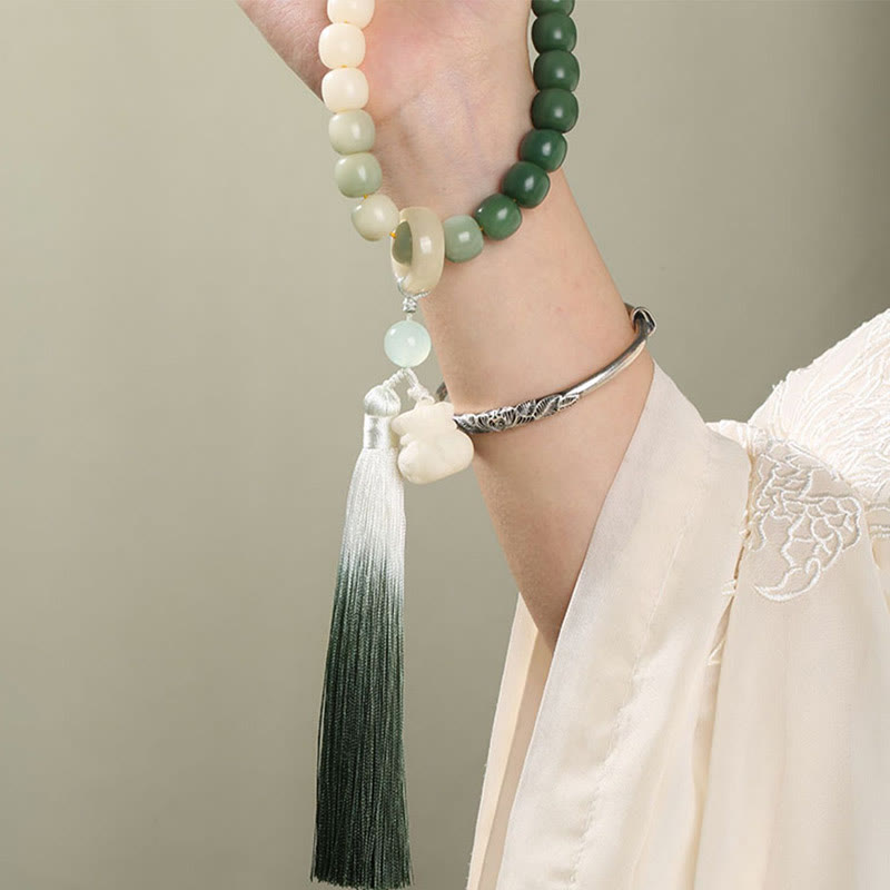 Bodhi Seed Lotus Wisdom Wrist Mala – Prayer bead bracelet worn on raised hand in Hanfu, ombre green tassel flowing, zen aesthetic