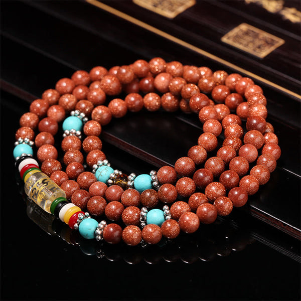 Goldstone Mala Bracelet – coiled mala on dark lacquered surface with traditional box, goldstone beads