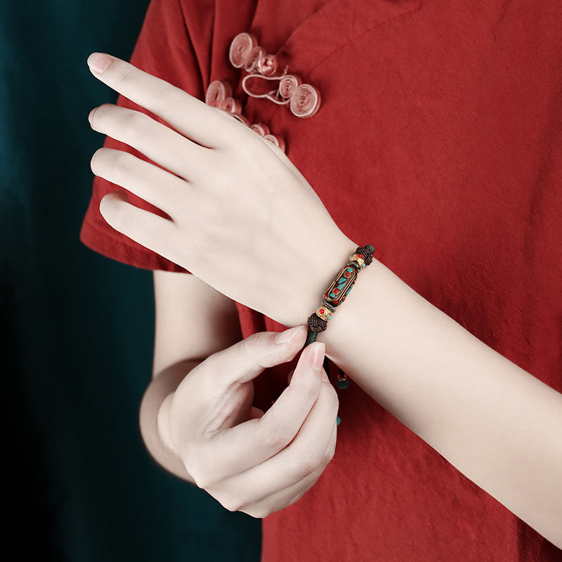 Tibetan Turquoise Om Mani Padme Hum Braided Bracelet – Worn on wrist against red traditional garment, turquoise focal bead