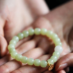 Jade Lotus Abundance Bracelet – Celadon barrel beads with gold lotus charm held in cupped hands, lotus bracelet