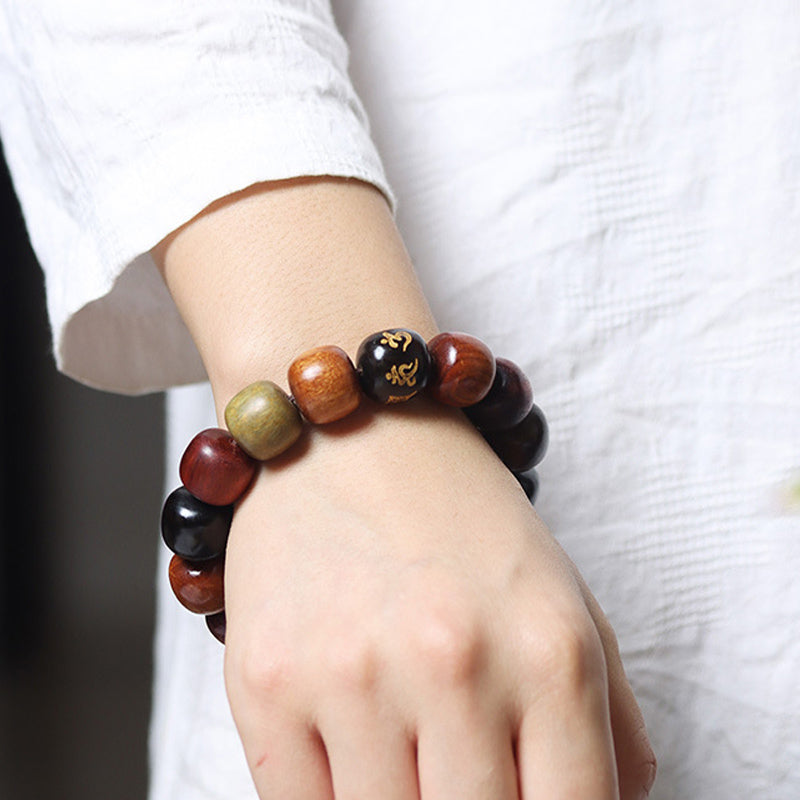 Wood Bead Bracelet – worn on wrist with white linen, multi-tone beads and gold mantra focal, men's jewelry