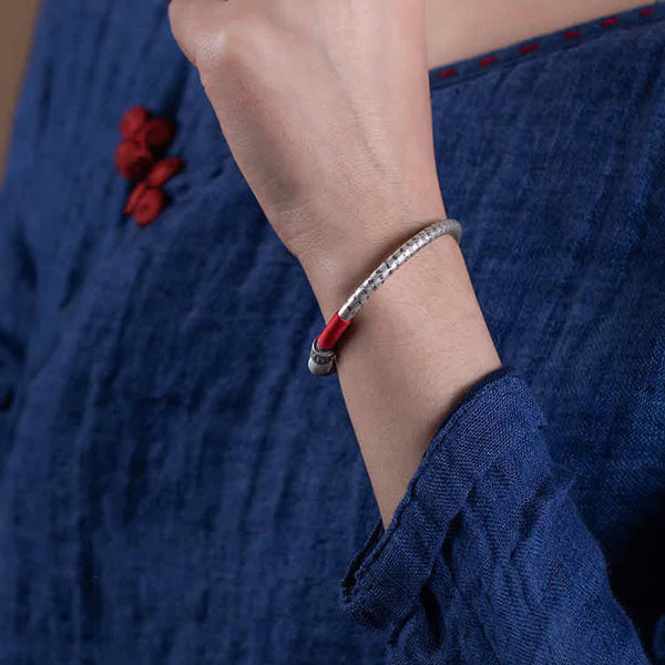 Tibetan Red String Bracelet – worn on wrist with navy fabric and knot button, red cord bangle