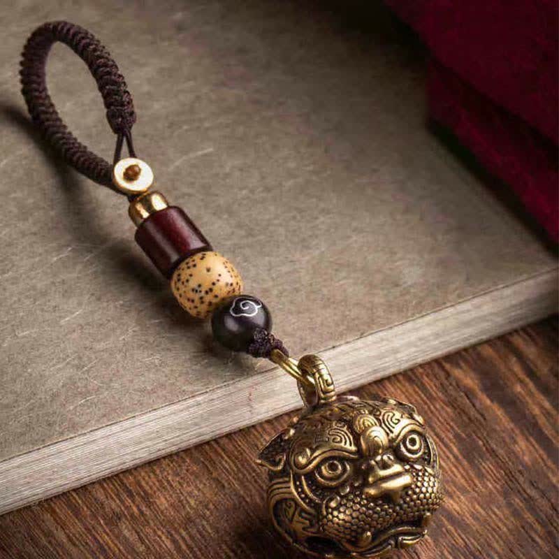 Pixiu Wealth Copper Key Chain – on vintage book front view with red cloth background, brass pixiu wealth charm