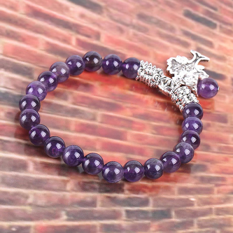 Tree of Life amethyst stretch bracelet with deep violet beads, silver Tree of Life charm, antique silver spacer beads against brick background.