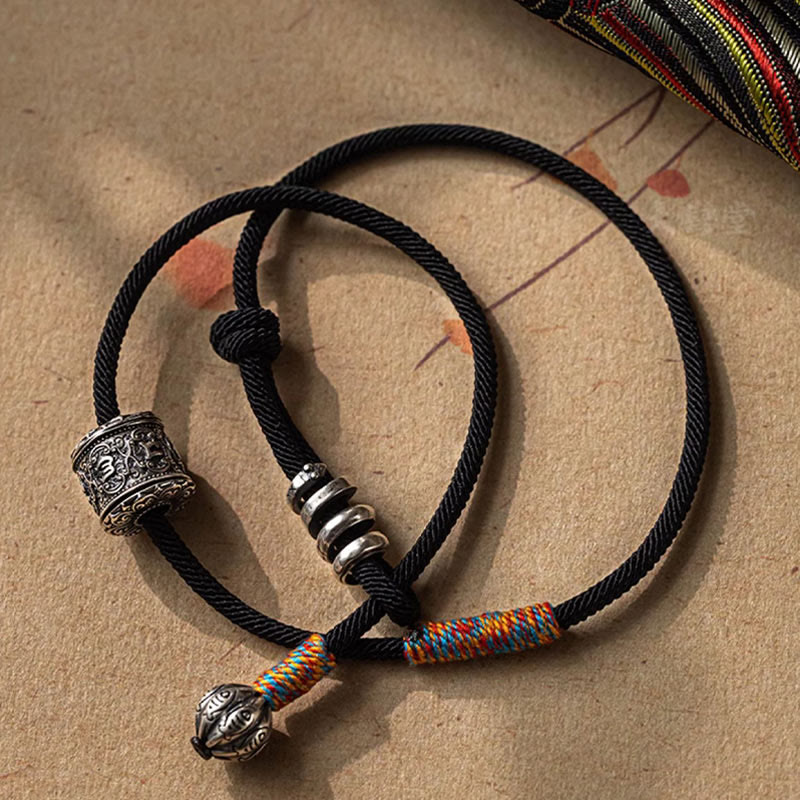 Tibetan Om Mani Padme Hum Wrap Bracelet – Wrist close-up with denim cuff showing silver engraved bead and multiple silver rings, outdoor lighting