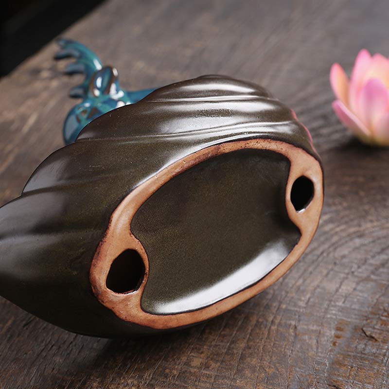 Little Deer Ceramic Lotus Incense Burner – Dark glossy ceramic base with drainage detail on rustic wood, teal deer behind