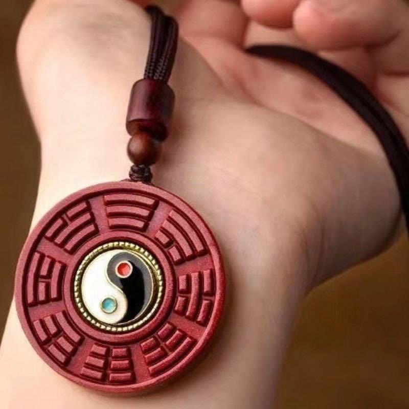 Cinnabar Bagua Rotatable Yin Yang Necklace – Red cinnabar rotatable amulet in hand, Yin-Yang Bagua detail close-up