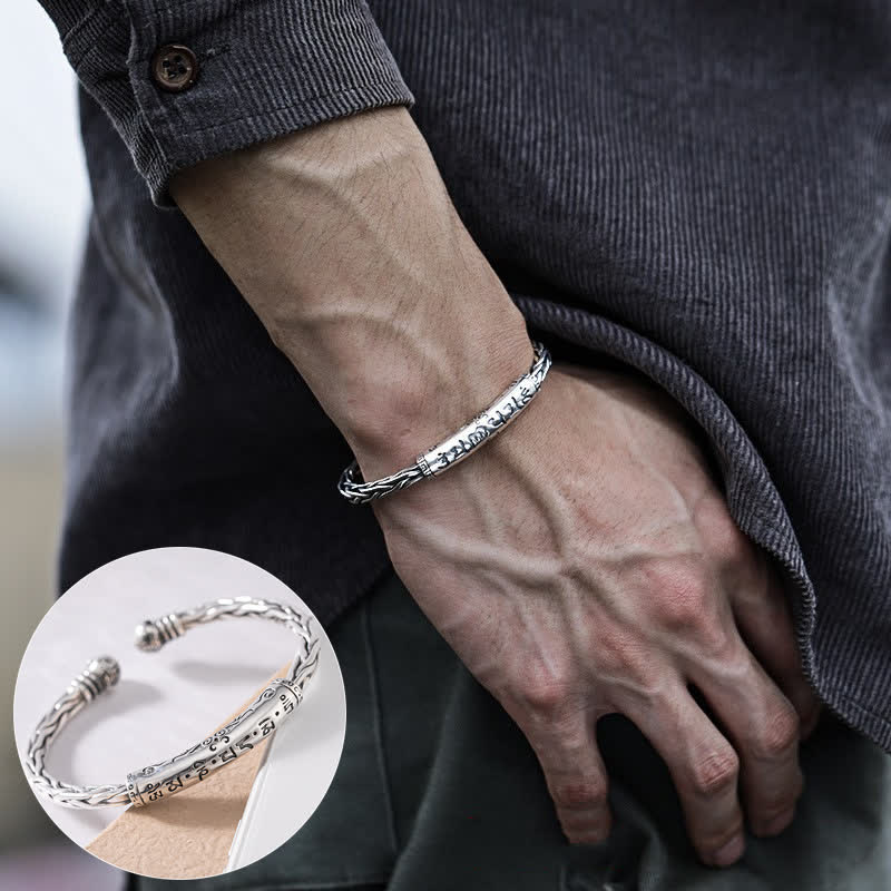 Men's oxidized silver Viking cuff bracelet with runic inscription central panel twisted rope borders worn on wrist with charcoal corduroy shirt lifestyle inset detail