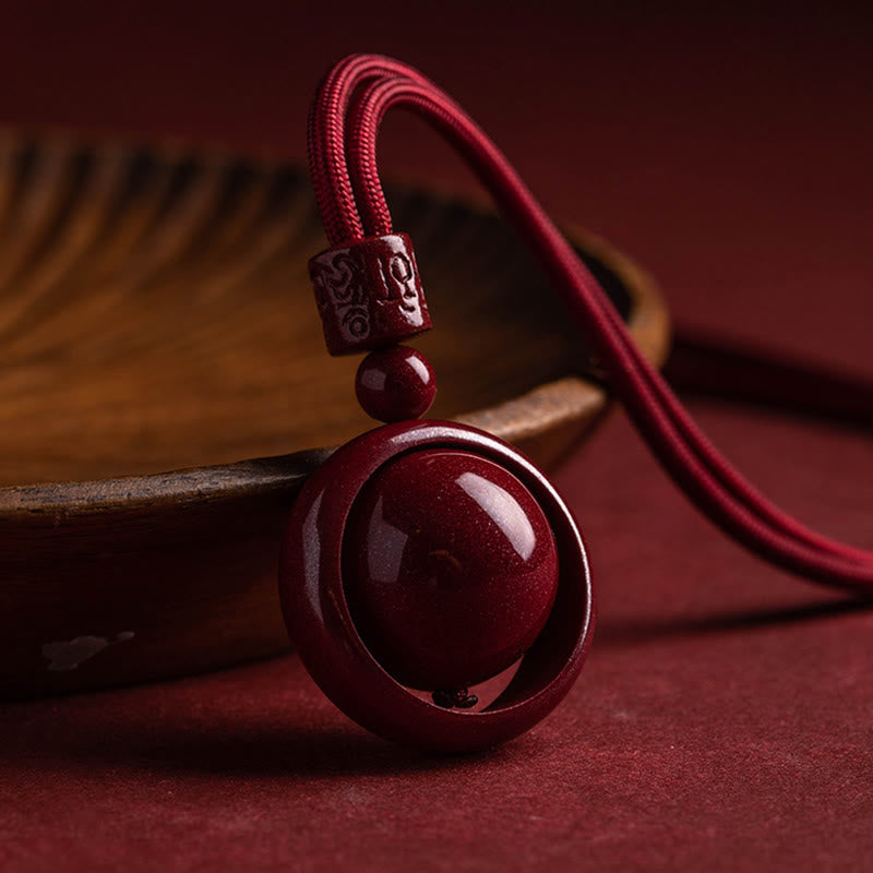 Cinnabar PiXiu Necklace – Red cord pendant resting by dark wooden bowl on red surface, good luck necklace