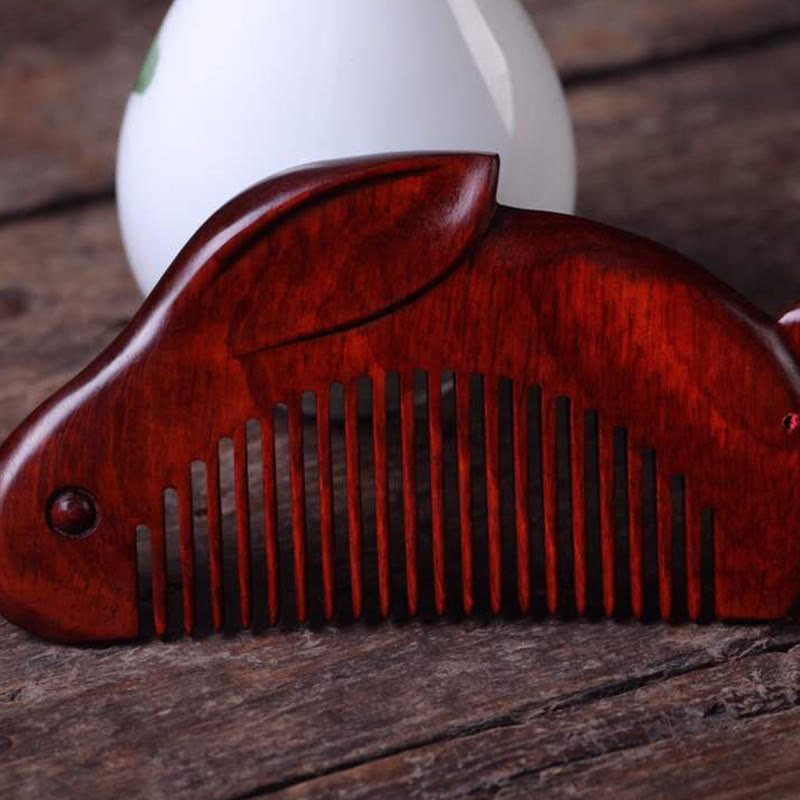 Red sandalwood bunny massage comb placed on rustic wooden table