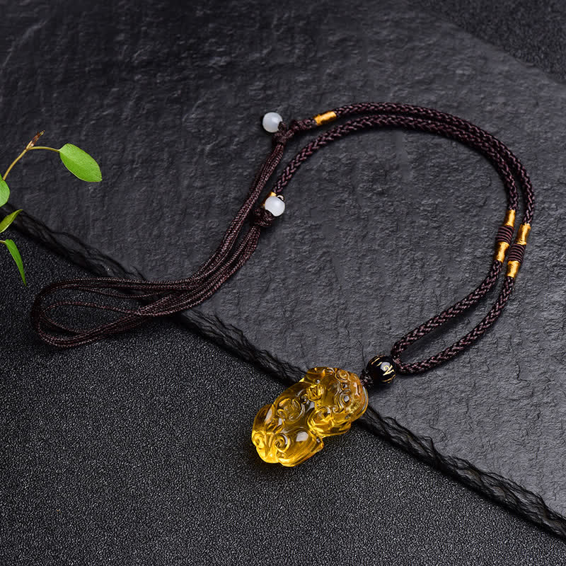 Citrine PiXiu Necklace Pendant – Full adjustable cord necklace laid flat on dark stone with leaf, gift
