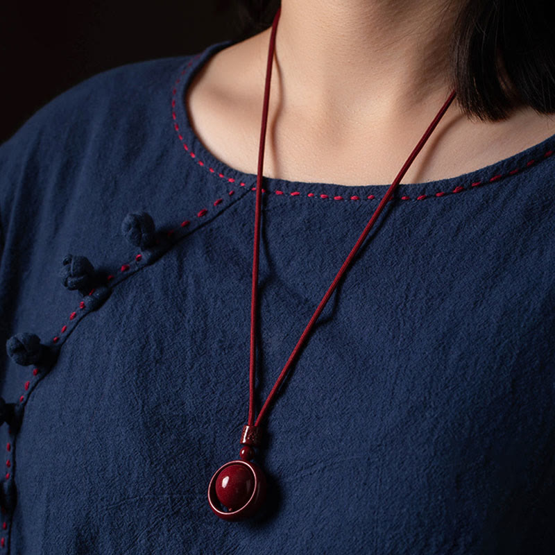 Cinnabar PiXiu Necklace – Worn on model in navy top chest level view, feng shui cinnabar jewelry