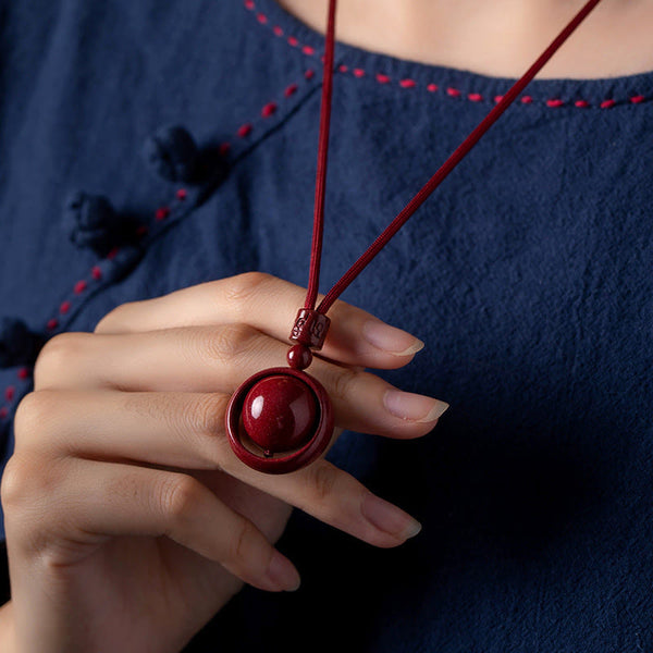 Cinnabar PiXiu Necklace – Model wearing with navy blue traditional outfit hand touching pendant, wealth necklace