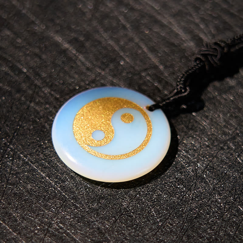 Yin Yang Crystal Necklace – Round opalite pendant with gold textured yin-yang design, iridescent white-blue stone on black co