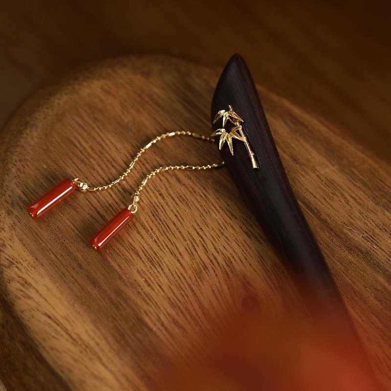 Ebony wood hairpin with red agate tassels placed on wooden tray