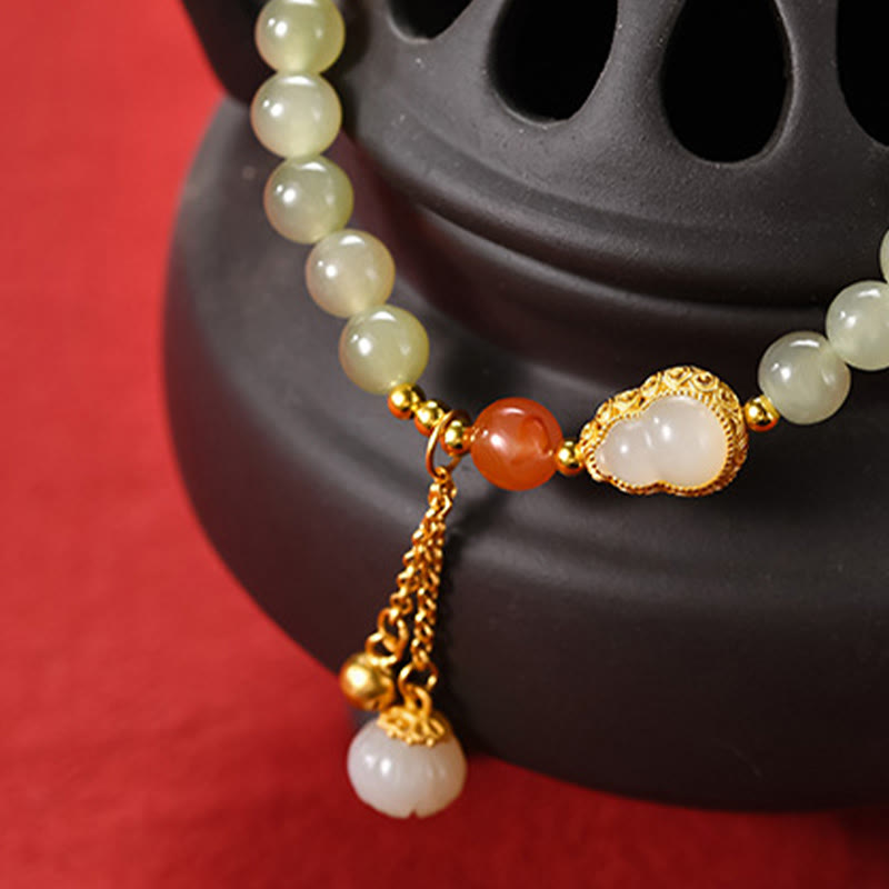 Jade Gourd Lotus Bracelet on blossom-embroidered cushion with wooden box edge, crimson bokeh, festive luxury