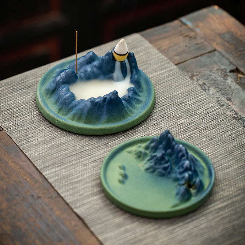 Ceramic Backflow Incense Burner – Two blue-green mountain burners on woven mat, one with active smoke, zen decor
