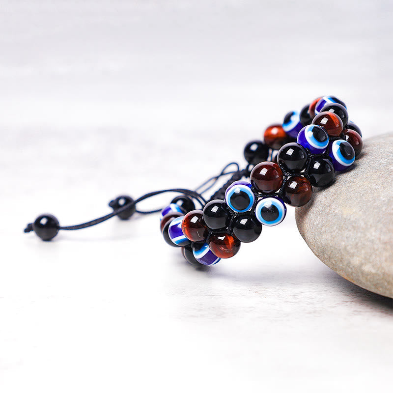 Evil Eye Hematite Tiger Eye Bracelet – bead cluster on whitewashed wood with gray river stone prop