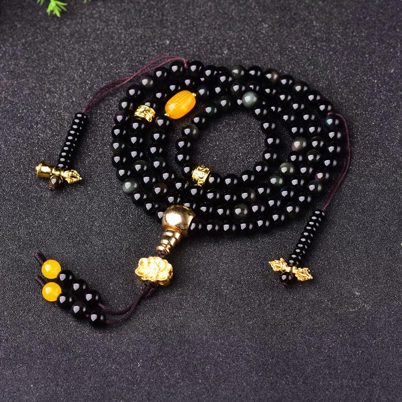 Black Obsidian Lotus Mala Bracelet - Coiled on dark fabric, glossy black beads with gold accents, obsidian