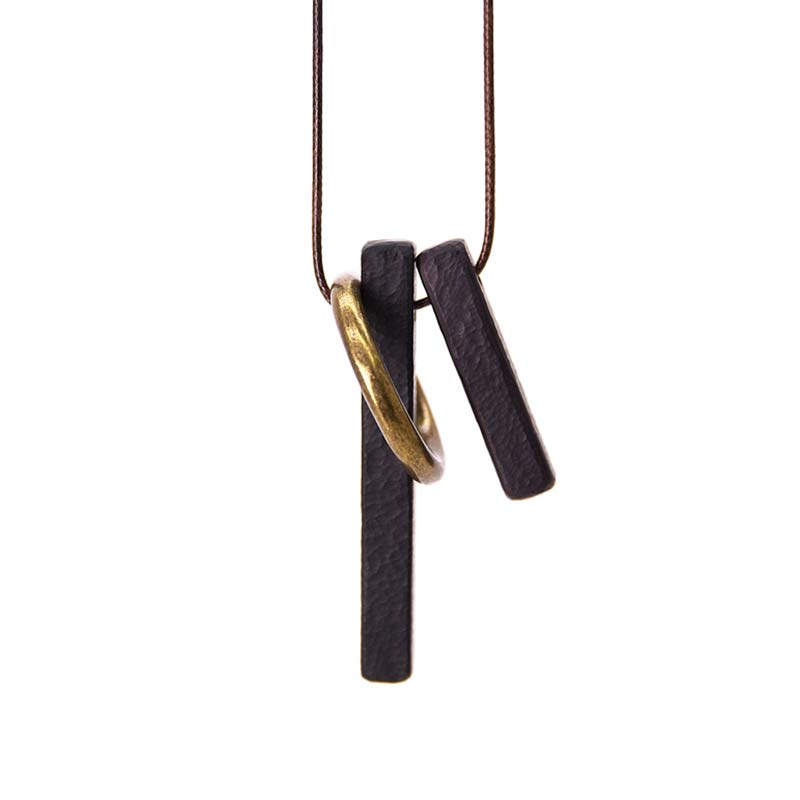 Zen Circle Ebony Wood Necklace - black hammered bars linked by gold ring, hanging from cord, white background