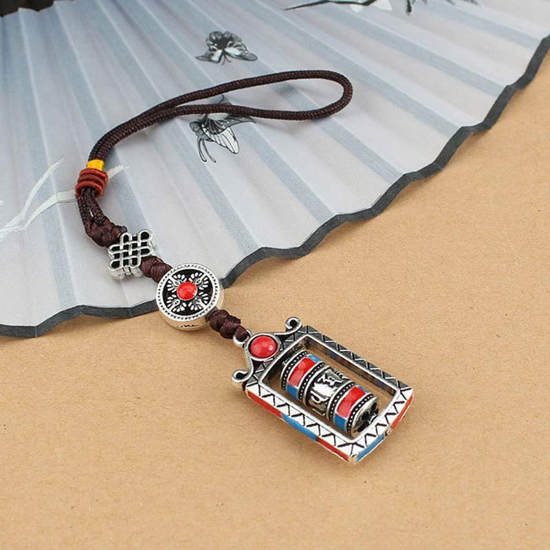 Om Mani Padme Hum Prayer Wheel Keychain – Elevated view on kraft paper with decorative fan prop, Tibetan pendant