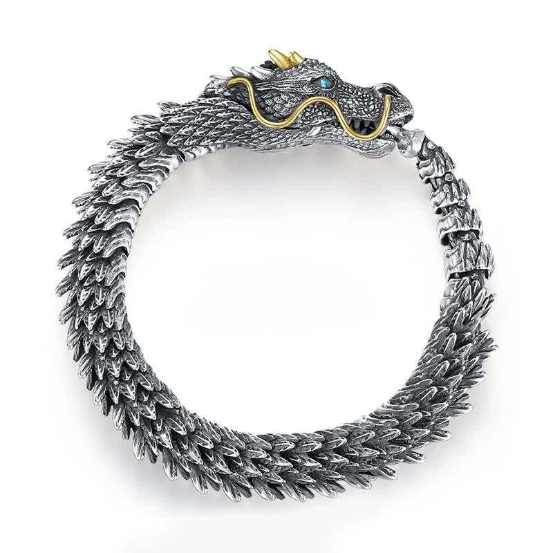 Dragon cuff bracelet on clean white background showing oxidized silver scales gold whiskers gold horns and blue gemstone eye with detailed sculptural craftsmanship