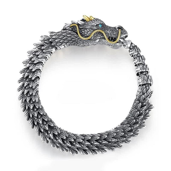 Dragon cuff bracelet on clean white background showing oxidized silver scales gold whiskers gold horns and blue gemstone eye with detailed sculptural craftsmanship